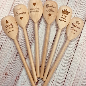 May include: Seven wooden spoons with personalized text. The spoons are engraved with names, titles, and phrases like "Chef Sameera", "Mama D's Kitchen", "Grandma's Kitchen", "King of the Kitchen", "Baking Queen", and "Star Baker Saijal".