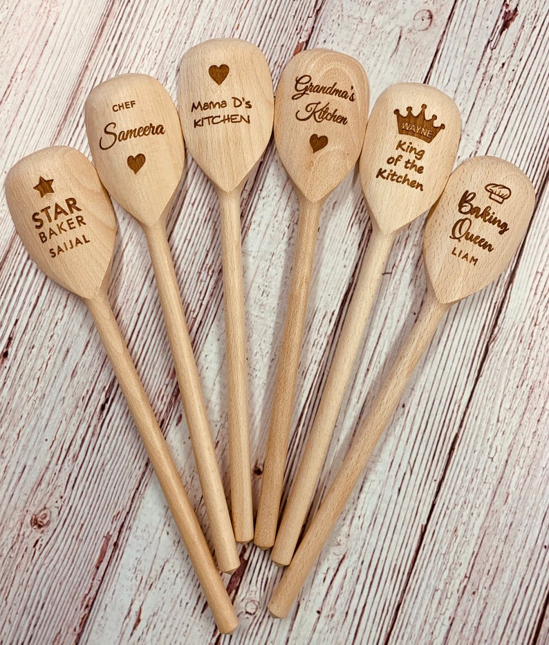 May include: Seven wooden spoons with personalized text. The spoons are engraved with names, titles, and phrases like "Chef Sameera", "Mama D's Kitchen", "Grandma's Kitchen", "King of the Kitchen", "Baking Queen", and "Star Baker Saijal".