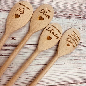 May include: Four wooden spoons with personalized engravings. The spoons are arranged in a row, with the top spoon reading "Commis Chef Liz", the second spoon reading "Chef Ruth", the third spoon reading "Scullery Maid Rachel", and the bottom spoon reading "Only the best Mum's get promoted to Grandma".