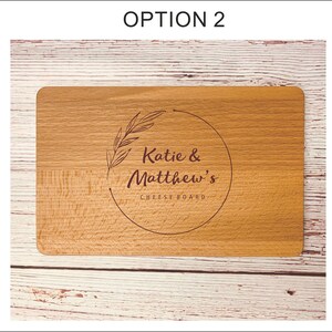 May include: Three wooden cutting boards with different engraved designs. The first board has a wine bottle and cheese design with the text "Suzie & Mark's Cheeseboard". The second board has a floral design with the text "Katie & Matthew's Cheeseboard". The third board has a simple floral design with the text "Katie & Matthew's Cheeseboard".