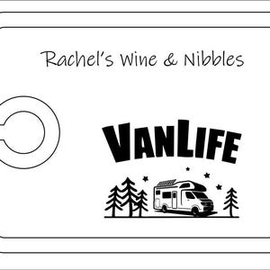 May include: A rectangular white serving board with a rounded cutout on the left side. The text Rachel's Wine & Nibbles is printed at the top. Below, a black graphic features the word VANLIFE above a camper van, pine trees, and stars.