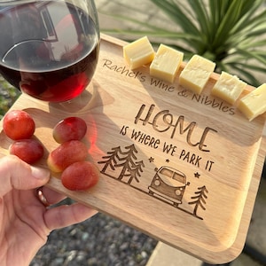 May include: A white ceramic mug with a black handle and the text "But First, Coffee" in a bold, black font. The mug is set against a blurred background, suggesting a cosy setting.