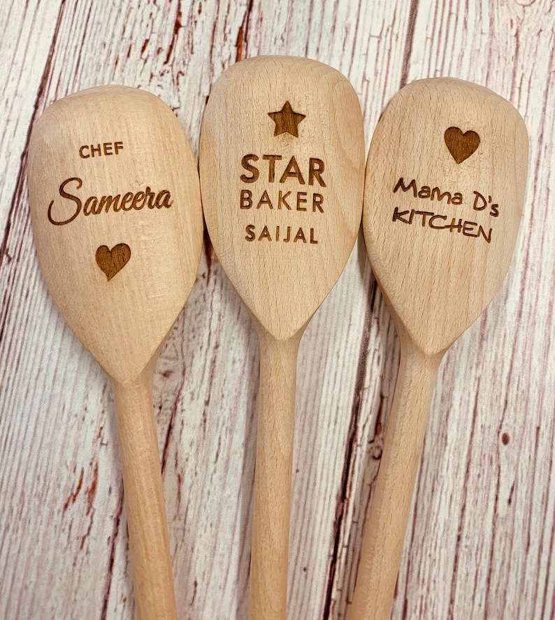 May include: Three wooden spoons with personalized engravings. The first spoon says "Chef Sameera" with a heart. The second spoon says "Star Baker Saijal" with a star. The third spoon says "Mama D's Kitchen" with a heart.