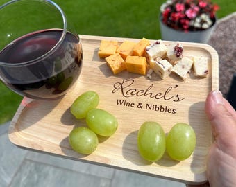 May include: A wooden serving tray with a personalised inscription that reads "Rachel's Wine & Nibbles". The tray features a glass of red wine, grapes, and a selection of cheese cubes.