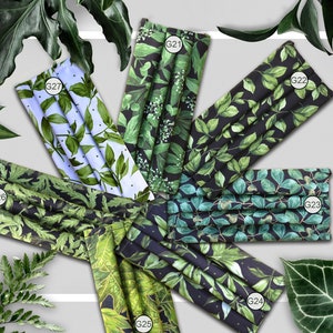 May include: Six different fabric face masks with green leaf patterns on a black or light blue background. The masks are labeled with the numbers G21, G22, G23, G24, G25, and G26.