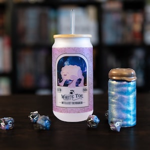 May include: A white can with a pink and purple label featuring a cartoon creature and the text "White Toe - Intellect Devourer". The can has a bamboo lid and a straw. There are also several iridescent dice and a small iridescent jar with a gold lid.