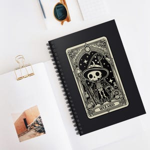 Puede incluir: Una ilustración en blanco y negro de un mago esqueleto sosteniendo un bastón. La ilustración está en una tarjeta blanca con un borde negro y detalles ornamentados. La tarjeta tiene la palabra "WIZARD" impresa en la parte inferior.
