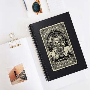 Puede incluir: Una ilustración en blanco y negro de una carta de tarot con un personaje con cara de calavera vestido con una túnica de mago. La carta se titula "SORCERER" y tiene un borde decorativo.