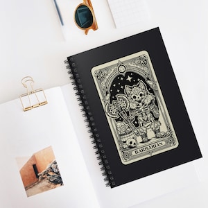 Puede incluir: Una ilustración en blanco y negro de una criatura esquelética similar a un lobo que sostiene un hacha. La ilustración está enmarcada en un borde decorativo y tiene la palabra "BARBARIAN" en la parte inferior. El fondo es negro con estrellas.