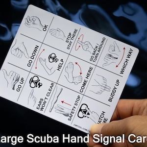 Op de afbeelding: Een witte rechthoekige kaart met zwarte illustraties van handgebaren voor duiken. De kaart bevat de tekst "Large Scuba Hand Signal Card" onderaan en toont verschillende handgebaren met bijbehorende instructies.