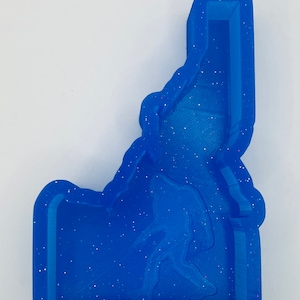 May include: Blue glitter resin mold of the state of Idaho with a silhouette of Bigfoot inside.