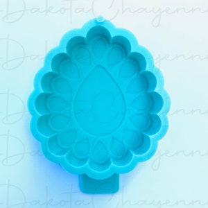 May include: A blue silicone mold shaped like a teardrop with a decorative border of small teardrops. The mold is designed for making resin crafts.