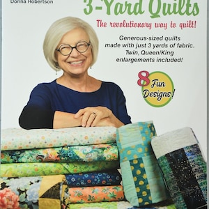Peut inclure: Une couverture de livre représentant une femme souriante tenant une pile de courtepointes colorées. Le titre du livre est "Quick'n Easy 3-Yard Quilts" et le sous-titre est "The revolutionary way to quilt!" La couverture comprend également le texte "8 Fun Designs!"