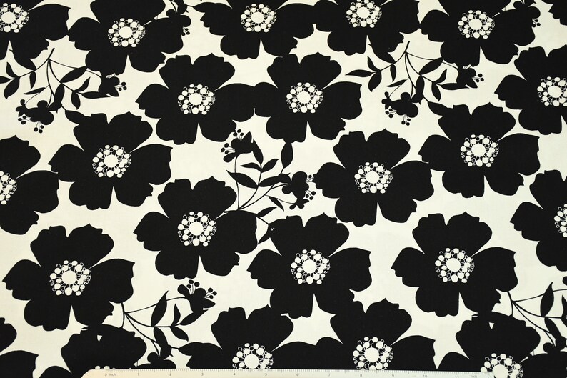 May include: Black and white floral fabric with a repeating pattern of large, stylized flowers. The flowers have a white center with a circle of smaller white circles.