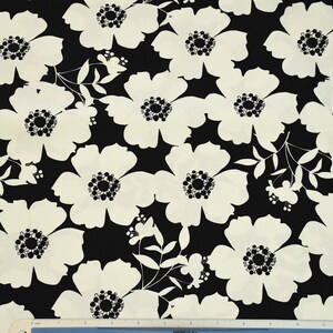 May include: Black and white fabric with a floral pattern. The flowers are large and have a simple design. The fabric is perfect for quilting, sewing, or crafting.