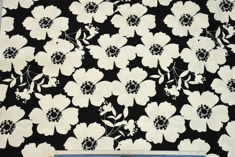 May include: Black and white fabric with a floral pattern. The flowers are large and have a simple design. The fabric is perfect for quilting, sewing, or crafting.