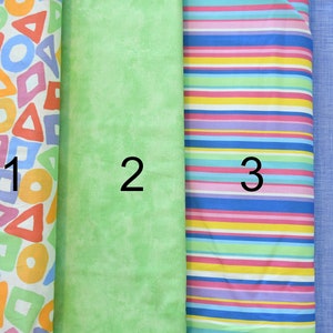 Peut inclure: Quatre échantillons de tissu, numérotés de 1 à 4. L'échantillon 1 présente un fond blanc avec des formes géométriques colorées. L'échantillon 2 est d'un vert clair uni. L'échantillon 3 a un fond blanc avec des rayures horizontales colorées. L'échantillon 4 est d'un bleu clair uni.