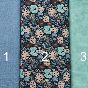May include: Three fabric swatches, numbered 1, 2, and 3. The first swatch is a light blue fabric with a small, white, repeating pattern. The second swatch is a dark blue fabric with a repeating pattern of light blue, pink, and orange coral. The third swatch is a light green fabric with a mottled, faded pattern.