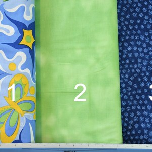 May include: Three fabric swatches, numbered 1, 2, and 3. The first swatch is blue with a white and yellow floral pattern. The second swatch is a solid light green. The third swatch is dark blue with a white floral pattern.
