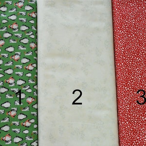 May include: Three fabric swatches, each with a different pattern. The first swatch is green with a white penguin pattern. The second swatch is white with a light gray floral pattern. The third swatch is red with a white polka dot pattern.