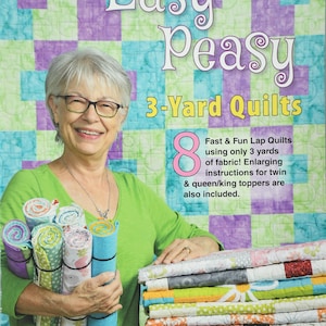 May include: A woman holds a stack of colorful fabric squares, with a book titled "Easy Peasy 3-Yard Quilts" in the background. The book cover features a patchwork quilt design and the text "Fast & Fun Lap Quilts using only 3 yards of fabric! Enlarging instructions for twin & queen/king toppers are also included."