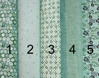 Puede incluir: Cinco muestras de tela en tonos verdes y azules. Las muestras están numeradas del 1 al 5. Las telas presentan varios patrones, incluyendo diseños geométricos, lunares e estampados florales.