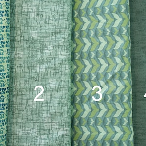 May include: Four different green fabric swatches with numbers 1 to 4 printed on them. The fabrics have different patterns, including a leaf pattern, a crosshatch pattern, a geometric pattern, and a solid green pattern.