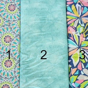 May include: Three fabric swatches, each with a different pattern. The first swatch has a repeating pattern of teal, green, and pink circles. The second swatch is a solid teal color. The third swatch has a repeating pattern of teal, green, pink, and white abstract shapes.