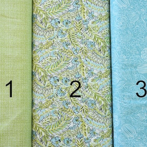 Puede incluir: Tres muestras de tela, una verde con una textura sutil, otra con fondo blanco y un patrón floral verde y azul, y una última azul claro con un patrón floral blanco. Las muestras están etiquetadas con 1, 2 y 3.