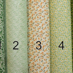 May include: Five fabric swatches featuring different floral designs. The swatches are numbered 1 to 5. The patterns include white daisies on a green background, white daisies on a light green background, orange and yellow flowers on a cream background, yellow flowers on a light green background, and yellow flowers on a dark green background.