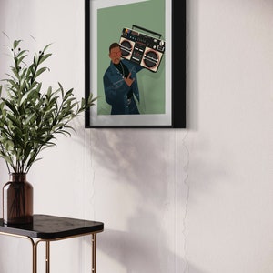 Op de afbeelding: Een ingelijste illustratie van een persoon die een blauwe jas en een zonnebril draagt en een grote ghettoblaster vasthoudt voor een groene achtergrond.