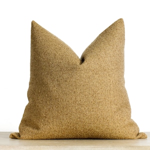 May include: A large, textured decorative pillow in a warm, golden-brown hue. The pillow has a classic shape with a pointed top and a soft, inviting appearance. The fabric appears to be woven, adding depth and visual interest to the design.