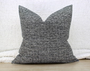 Op de afbeelding: Vierkant decoratief kussen met een geweven stof in grijstinten, zwart en een vleugje beige. Het kussen heeft een klassieke vorm en is ontworpen voor de interieurdecoratie.