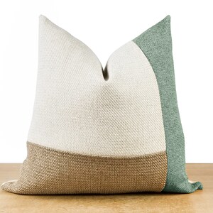 Pode incluir: Uma almofada decorativa com um design de blocos de cores. A almofada apresenta uma parte superior creme, uma parte inferior castanha e um painel lateral verde. A almofada &eacute; feita de um tecido texturizado e &eacute; projetada para decora&ccedil;&atilde;o de casa.