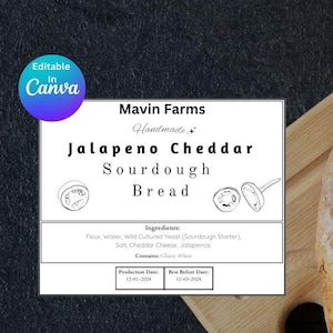 Puede incluir: Un primer plano de una hogaza de pan de masa madre sobre una tabla de cortar de madera. El pan está etiquetado como "Pan de masa madre con jalapeño y cheddar" y está hecho a mano por Mavin Farms.