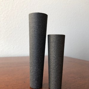 Puede incluir: Dos jarrones de cer&aacute;mica negra de diferentes tama&ntilde;os. El jarr&oacute;n m&aacute;s grande es m&aacute;s alto y m&aacute;s estrecho que el jarr&oacute;n m&aacute;s peque&ntilde;o.