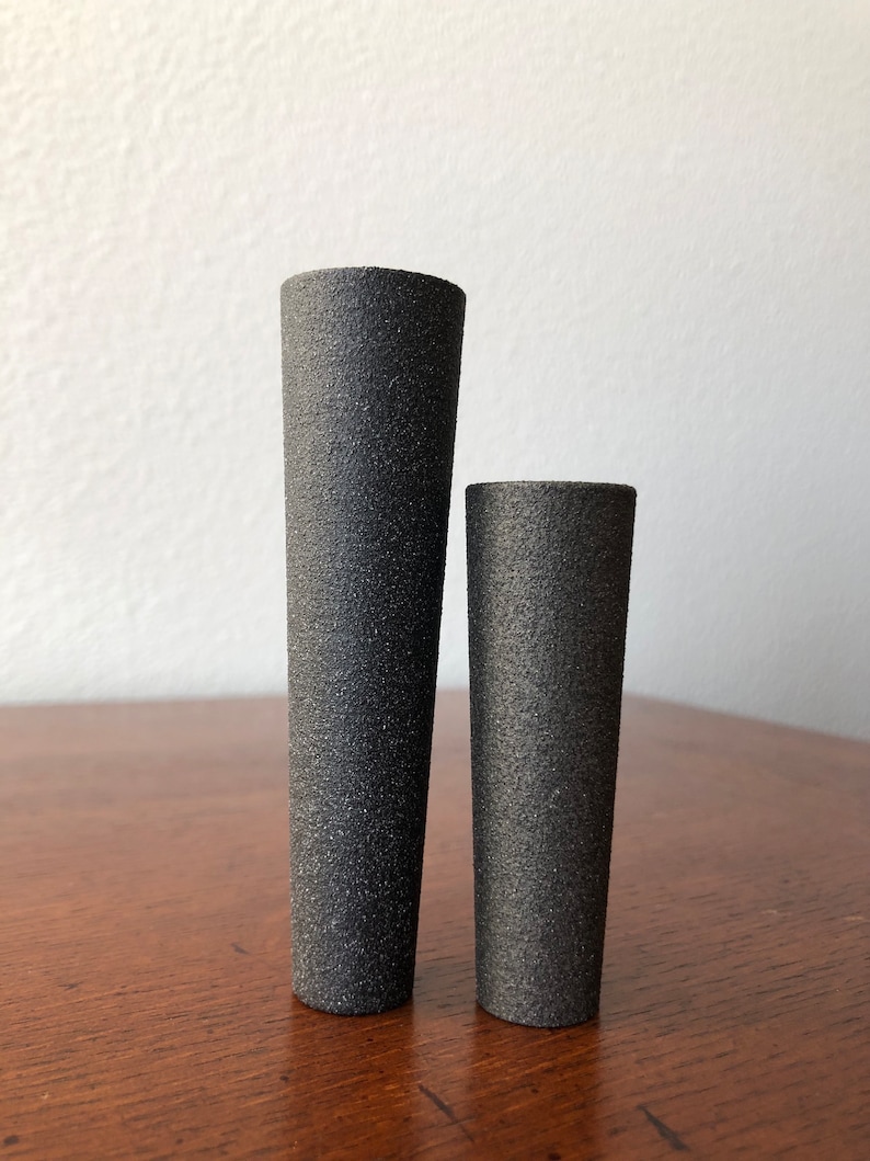 Puede incluir: Dos jarrones de cer&aacute;mica negra de diferentes tama&ntilde;os. El jarr&oacute;n m&aacute;s grande es m&aacute;s alto y m&aacute;s estrecho que el jarr&oacute;n m&aacute;s peque&ntilde;o.