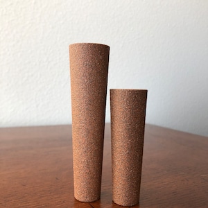 Puede incluir: Dos jarrones cil&iacute;ndricos de cer&aacute;mica marr&oacute;n con una superficie texturizada rugosa. El jarr&oacute;n m&aacute;s grande es m&aacute;s alto que el jarr&oacute;n m&aacute;s peque&ntilde;o.