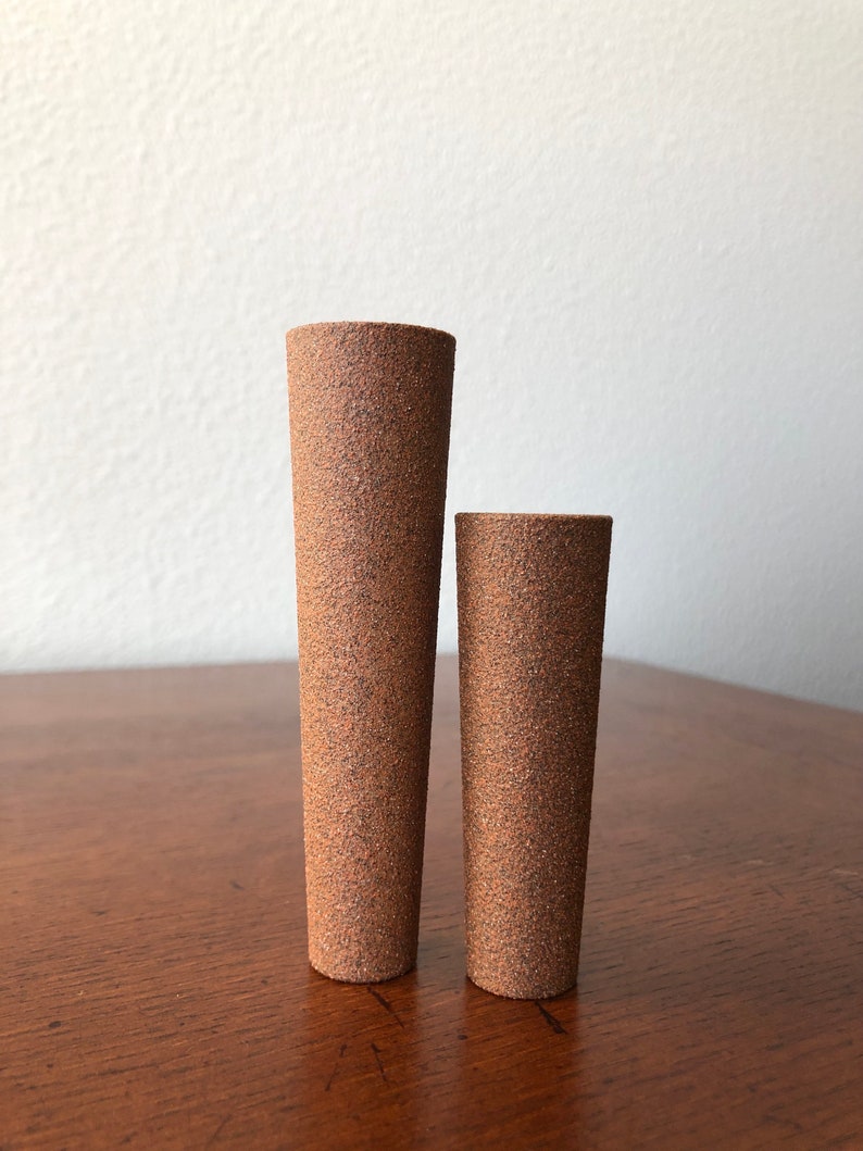 Puede incluir: Dos jarrones cil&iacute;ndricos de cer&aacute;mica marr&oacute;n con una superficie texturizada rugosa. El jarr&oacute;n m&aacute;s grande es m&aacute;s alto que el jarr&oacute;n m&aacute;s peque&ntilde;o.