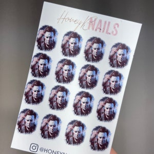 May include: A white sticker sheet featuring fifteen identical circular illustrations of a character with a pale mask, dark hair, and a dark outfit. The text Honey NAILS is printed at the top, and the text @HONEYNAILS is printed at the bottom.