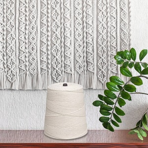 May include: A spool of natural white cotton cord, perfect for macrame projects. The cord is wound tightly on the spool and has a natural, rustic look.