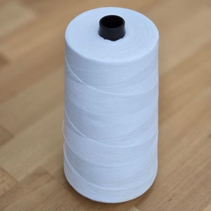 May include: A white spool of thread with a black plastic center.