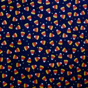 May include: A dark blue fabric with a repeating pattern of candy corn and small, colorful dots. The candy corn is in the classic orange, yellow, and white colors, creating a festive Halloween theme.
