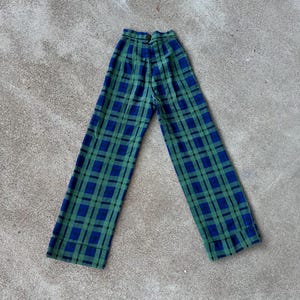 May include: Green and blue plaid pants. The pants have a high waist and a button closure. The plaid pattern is a classic design, with a grid of intersecting lines in green and blue. The pants are made of a soft, woven fabric.