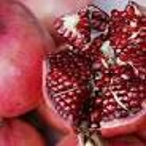May include: Close-up of a red pomegranate fruit cut open, revealing the juicy, red seeds inside.