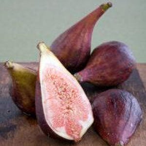 May include: A group of five ripe figs, some whole and some cut in half, on a wooden surface. The figs are a deep purple color with a pink interior.