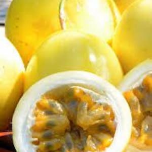 May include: Close-up of a yellow passion fruit cut in half, revealing the juicy, orange flesh and black seeds. The fruit is surrounded by whole yellow passion fruits.