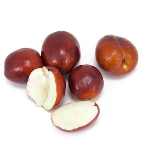 May include: Close-up of five red-brown jujubes, some whole and some cut in half, revealing the white flesh inside. The jujubes are arranged on a white surface.