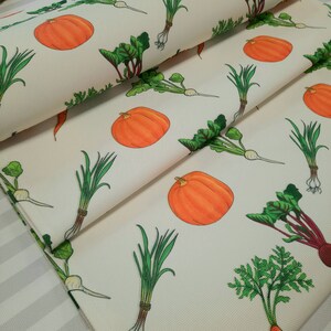 May include: White fabric with a repeating pattern of orange pumpkins, green onions, and leafy green vegetables.