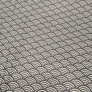 May include: A close-up of a fabric with a repeating pattern of black and white overlapping semi-circles. The pattern resembles scales or waves.